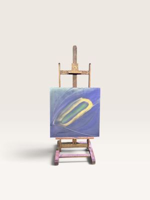 un petit chevalet sur lequel est posé un tableau, posé sur une surface blanche