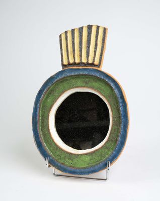 un vase bleu et vert posé sur une surface blanche