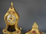 a gold clock sitting next to a small gold clock on a table