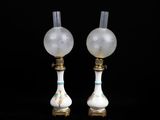 paire de lampes en verre blanc ornées de finitions dorées sur fond noir