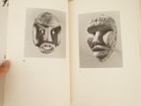 someone is holding a book open to a picture of two masks