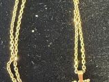 gold plated necklace with a cross pendant and a pair of scissors on a black background