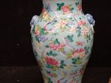 a blue vase with pink flowers on it next to a piece of bread