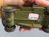 a hand holding a green toy truck with a sticker on it
