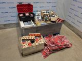 Des cartons contenant des objets divers sont posés par terre devant un mur.