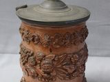 an old wooden canister with a metal lid sitting on a white surface