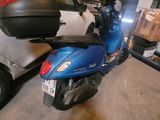 a blue scooter parked in a garage next to a white car