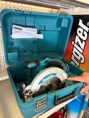 une personne tenant une scie circulaire dans une boîte à outils