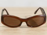 brown sunglasses on a wooden table with a white wall in the background