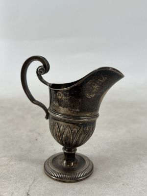 un petit pichet en argent posé sur une table