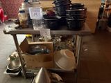 de nombreuses casseroles et poêles posées sur une table dans la cuisine