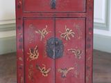 une image représentant une petite armoire rouge ornée de fleurs dorées