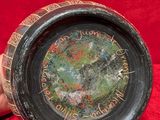 a person holding a bowl with writing on it on a red cloth