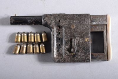 un vieux pistolet sur lequel sont posées plusieurs douilles