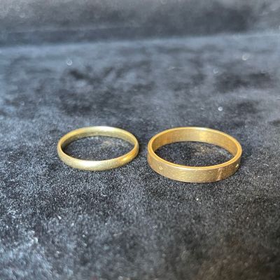 two gold wedding rings sitting on top of a black cloth