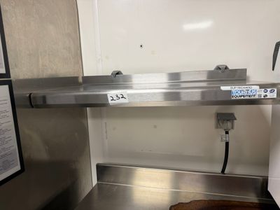 un comptoir en acier inoxydable avec un évier et une enseigne accrochée au mur