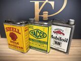 three cans of oil are sitting on a table next to a sign