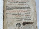 an old book sitting on top of a wooden block on a white surface