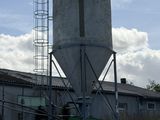 a tall cement silo sitting in the middle of a field