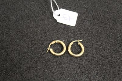 a pair of gold hoop earrings on a black surface with a price tag