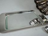 a silver tray with a mirror and spoons on a table