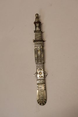 a small metal clock on the wall next to a white wall