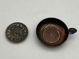 a small coin next to a small cup on a table