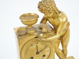 a gold statue of a boy with a bowl on top of a clock