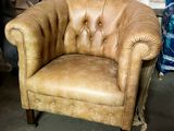 a tan leather chair sitting in a room with other furniture