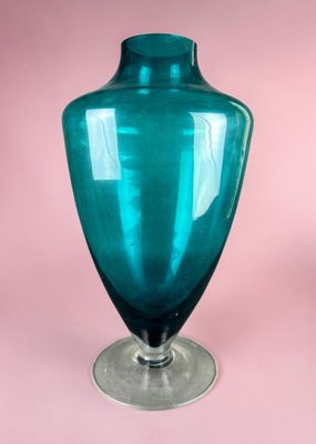 a blue glass vase sitting on top of a metal stand