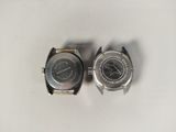 two watches sitting on top of each other on a white surface