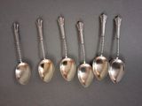 six spoons are lined up in a row on a table