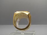 une photo d'une bague en or posée sur un socle transparent