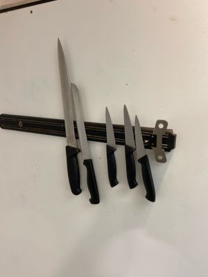 four knives hanging on the wall next to a knife holder