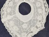 an old white lace bib with a hole in the middle of it