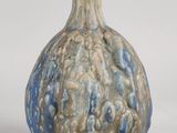 un vase bleu et brun posé sur une surface blanche