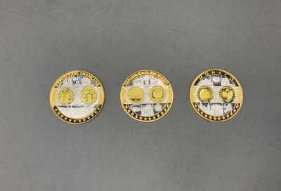 trois pièces d'or et d'argent posées sur une surface grise