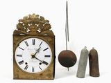 une petite horloge avec un pendule et une cloche à côté