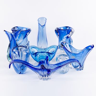 plusieurs vases en verre bleu empilés les uns sur les autres sur une surface blanche
