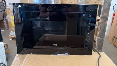 a black microwave sitting on a cardboard box in a warehouse