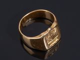 a close up of a gold signet ring on a black surface