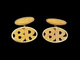 two gold cufflinks with initials on them on a black background
