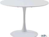 La table est blanche et possède un piètement circulaire.