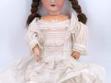 an old doll sitting on the ground with a white dress on