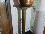 a plant in a pot on a pedestal in a room