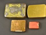 three small tins of different colors and sizes on a table