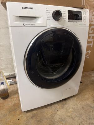 a white washing machine sitting on the floor next to a box