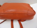 a close up of an orange purse on a white surface
