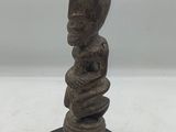 un gros plan d'une statue posée sur un socle en bois, sur une surface blanche
