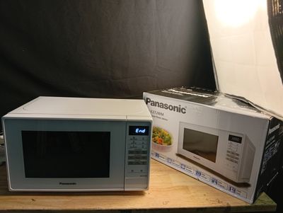 un micro-ondes blanc posé sur une table à côté d'une boîte de nourriture